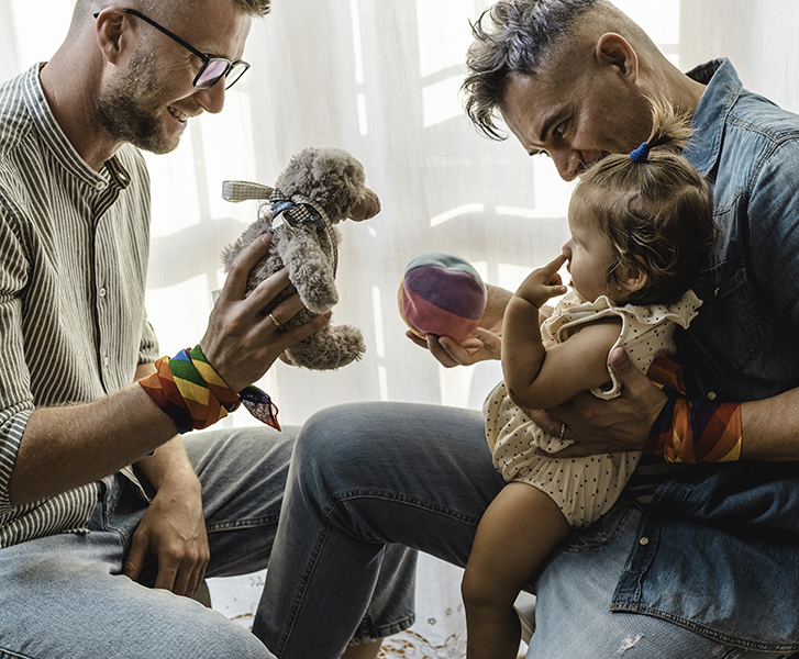Two  fathers playing with their daughter 